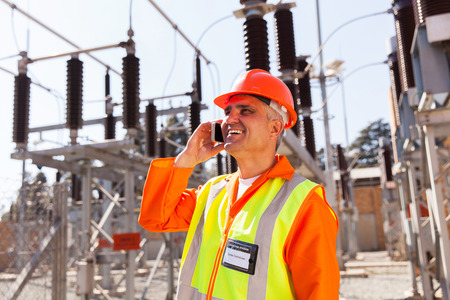middle aged technician talking on cell phone in substation