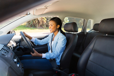 happy african woman driving a new car
