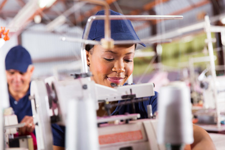pretty african textile worker sewing with industrial sewing machine