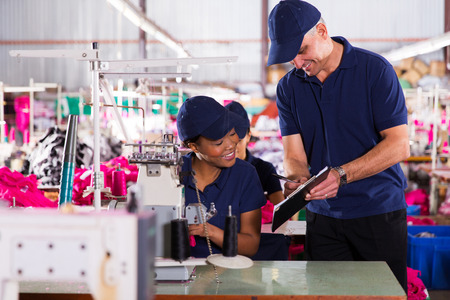 happy textile factory supervisor recording machinist performance