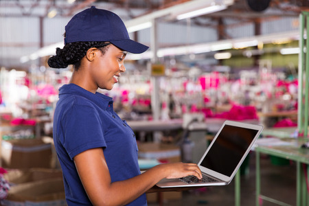 side view of clothing factory manager using laptop computerの写真素材