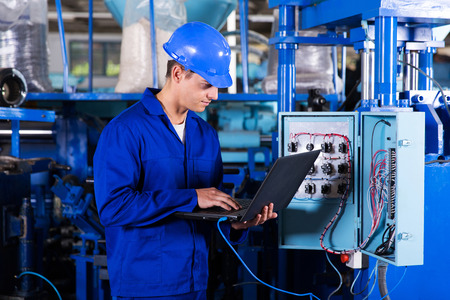 industrial programmer checking control box status with laptop computer