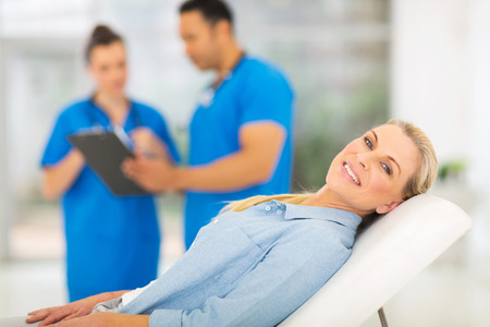 happy senior woman lying on doctor's examining bed and waiting for medical checkupの写真素材