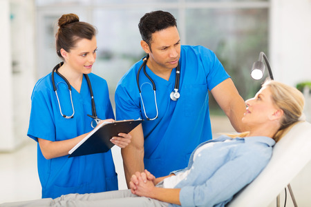caring health workers talking to middle aged patient before checkupの写真素材