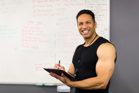 professional middle aged male trainer writing on clipboardの写真素材