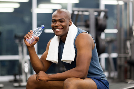 happy young african man drinking water after exerciseの写真素材