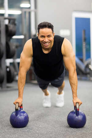 fit mid age man in plank position with kettle bells at the gymの写真素材