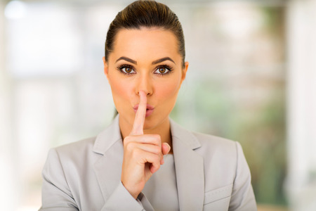 pretty young businesswoman saying shhh