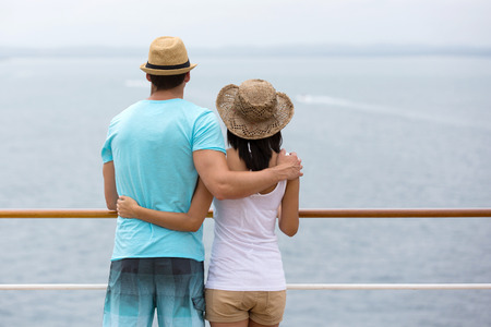 rear view of romantic young couple looking at the sea from cruise shipの写真素材