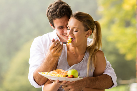 romantic man feeding wife scrambled eggs for breakfastの写真素材