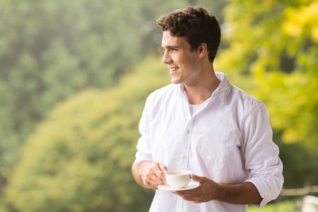 thoughtful young man having cup of coffee outdoorsの写真素材