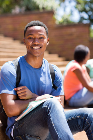 good looking male african college student sitting on stepsの写真素材