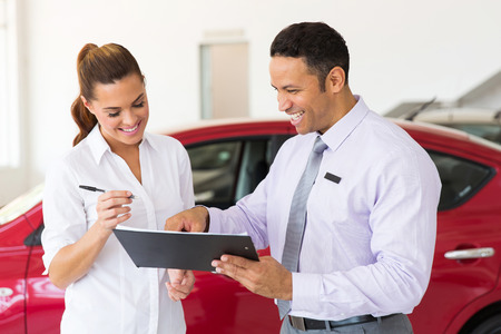 happy woman buying a new car at vehicle showroomの写真素材