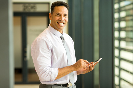 happy middle aged business executive using smart phone in officeの写真素材