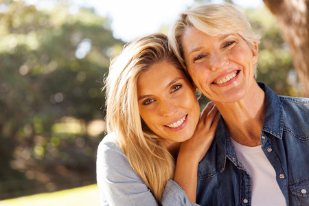 happy middle aged blond mother and adult daughter outdoorsの写真素材