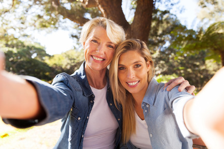 happy senior woman and daughter taking selfie togetherの写真素材