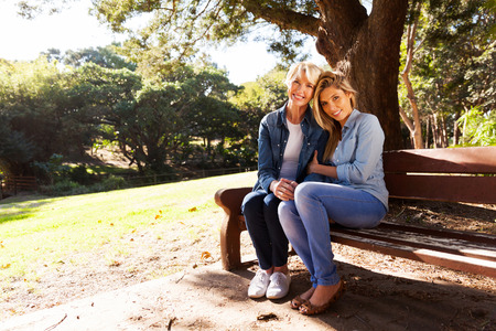 beautiful mother and daughter relaxing on park benchの写真素材