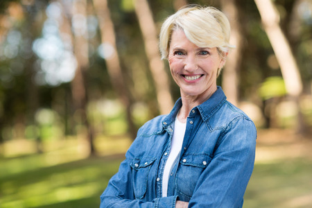 beautiful middle aged woman with arms folded outdoors