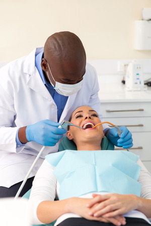 african american dentist cleaning and polishing teeth of a patientの写真素材
