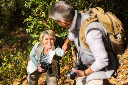 caring man helping his wife climbing mountainの写真素材