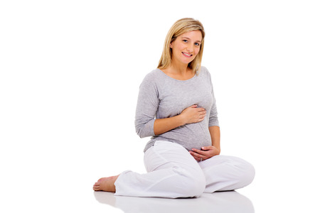 attractive young pregnant woman relaxing on white floorの写真素材