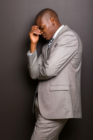 stressed african american man standing against black backgroundの写真素材