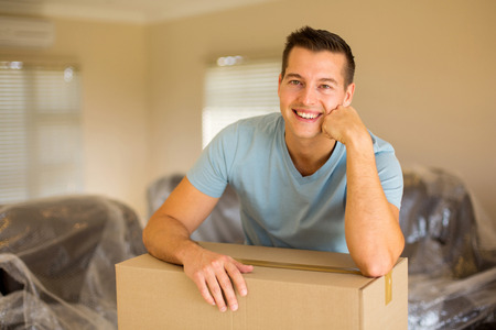 handsome man leaning on cardboard boxes in new homeの写真素材