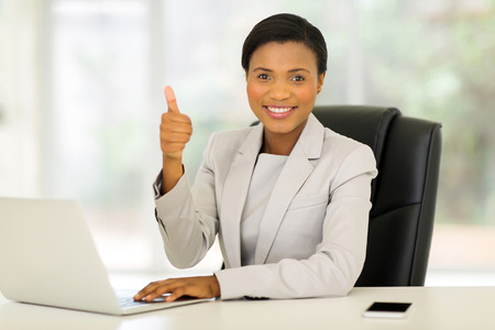 cheerful african american business executive giving thumb up in officeの写真素材