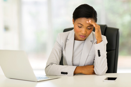stressed african businesswoman sitting in officeの写真素材