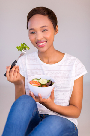 happy afro american woman eating green salad at homeの写真素材