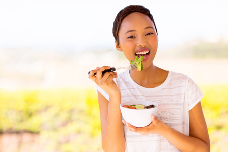 healthy african woman eating vegetable salad at homeの写真素材
