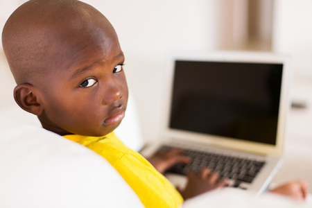 portrait of african boy with laptop computer looking backの写真素材
