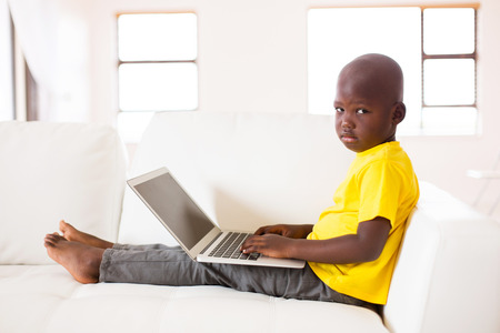 little african boy with a laptop computer sitting on couchの写真素材