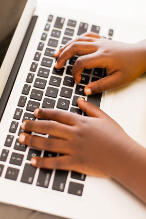 close up of little african boy hands playing on laptop computerの写真素材