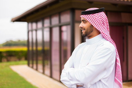 thoughtful arabian man standing in front of his house