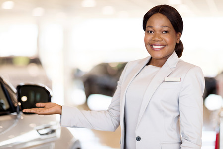beautiful african car saleswoman presenting new vehiclesの写真素材