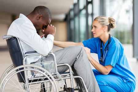 caring middle aged doctor comforting a disabled patientの写真素材