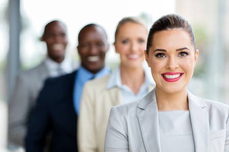 smiling young businesswoman with colleagues standing in a rowの写真素材