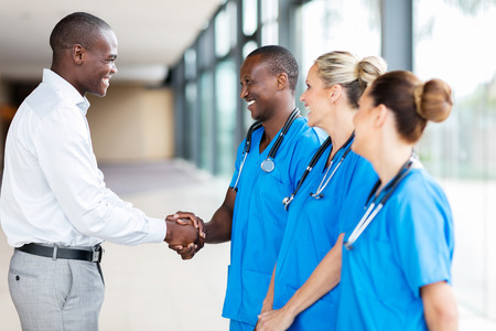 happy medical rep handshaking with group of doctors in hospitalの写真素材