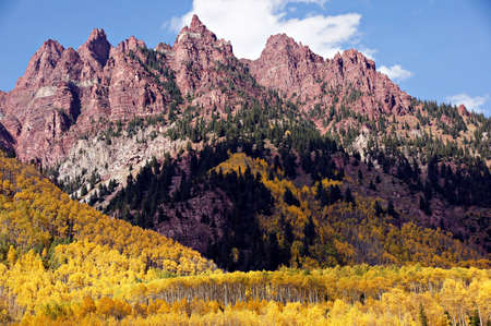 At Maroon Lake Colorado jagged spires form the backdrop to peak golden autumn aspen trees の写真素材