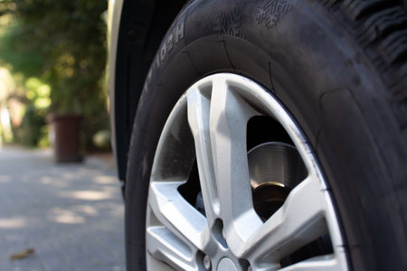 Close-up view of a car tire showcasing tread design on a sunny day in an urban areaの写真素材