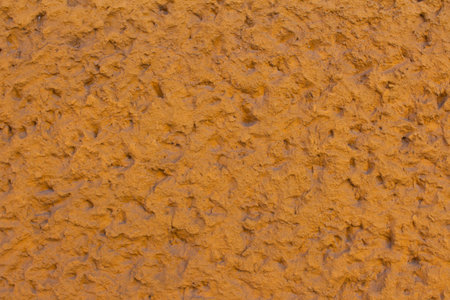 Earthy texture of a rustic wall showcasing rich orange tones and rough surface details