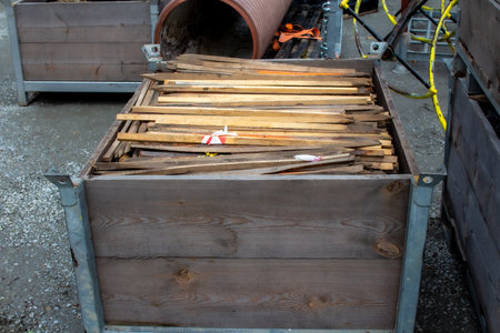 Wooden planks stored in a metal container at a construction site during daylight