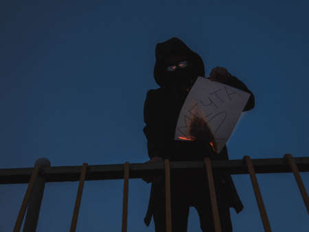 The guy holds a burning sheet of paper on which is written Dream. The guy is standing behind the...