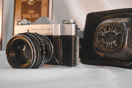The Soviet Zenit camera stands against the background of a leather case and Leo Tolstoy's book War and Peace.のeditorial素材