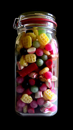 Jar filled with different candies on a black backgroundの写真素材