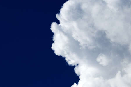 White fluffy cloud on a dark blue sky - cloudscape, overcast - cloudscape background