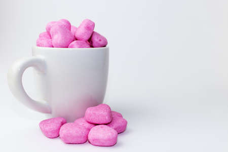 Heap of pink heart-shaped soft candies in a cup on a white background - Valentines candy