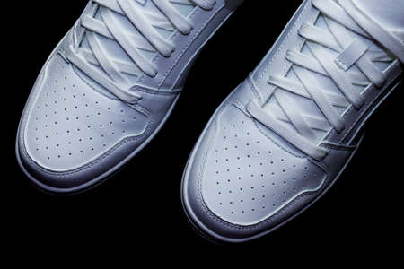 Top angle view of white sneakers on a black background - directly above view on trainers shoes