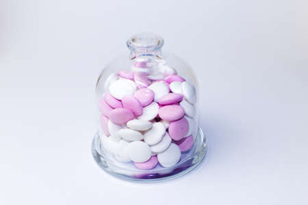 Pink and white peppermint candies in a glass jar on a white backgroundの写真素材